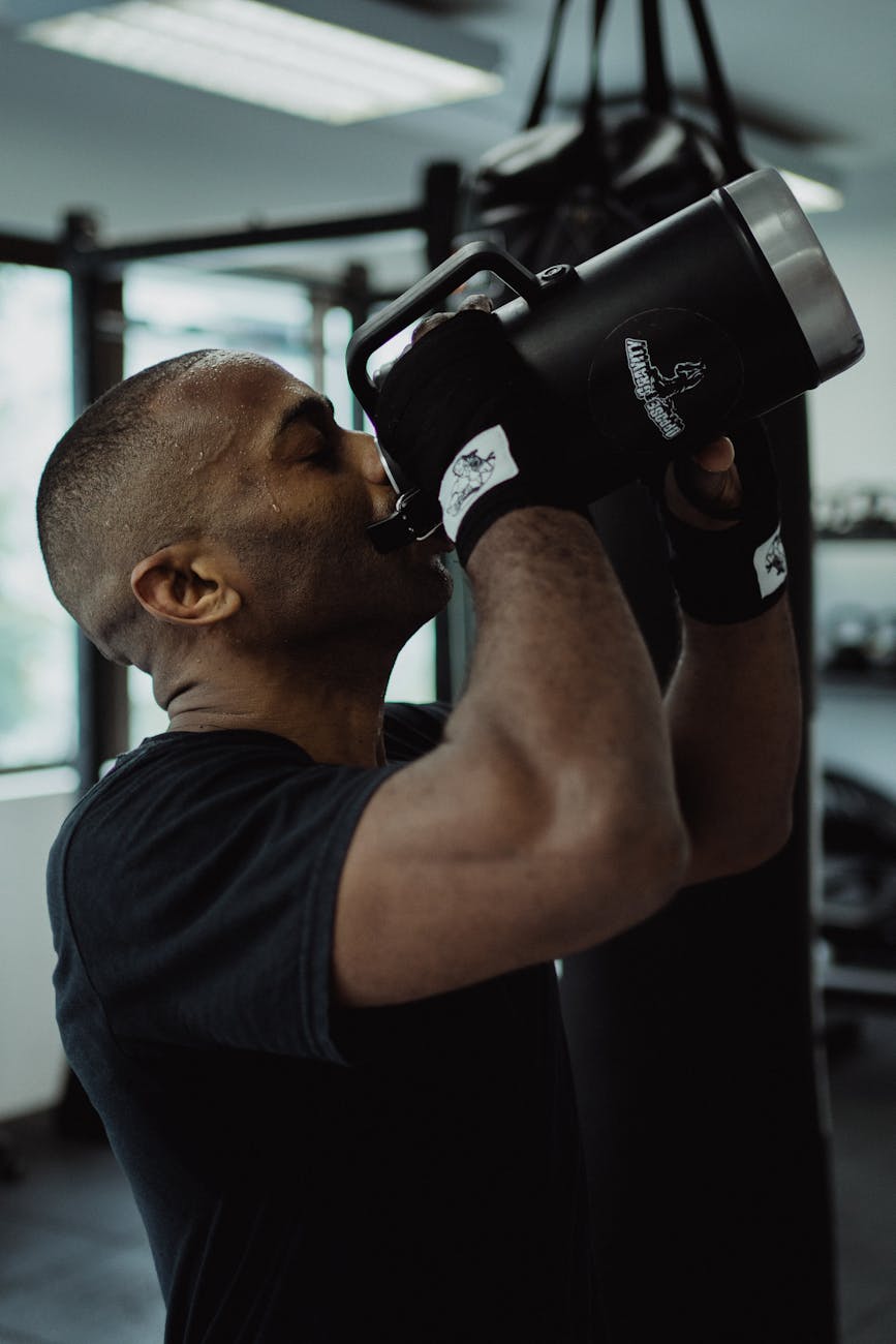 Side View Shot of a Man in Black Shirt Drinking on a Water Bottle