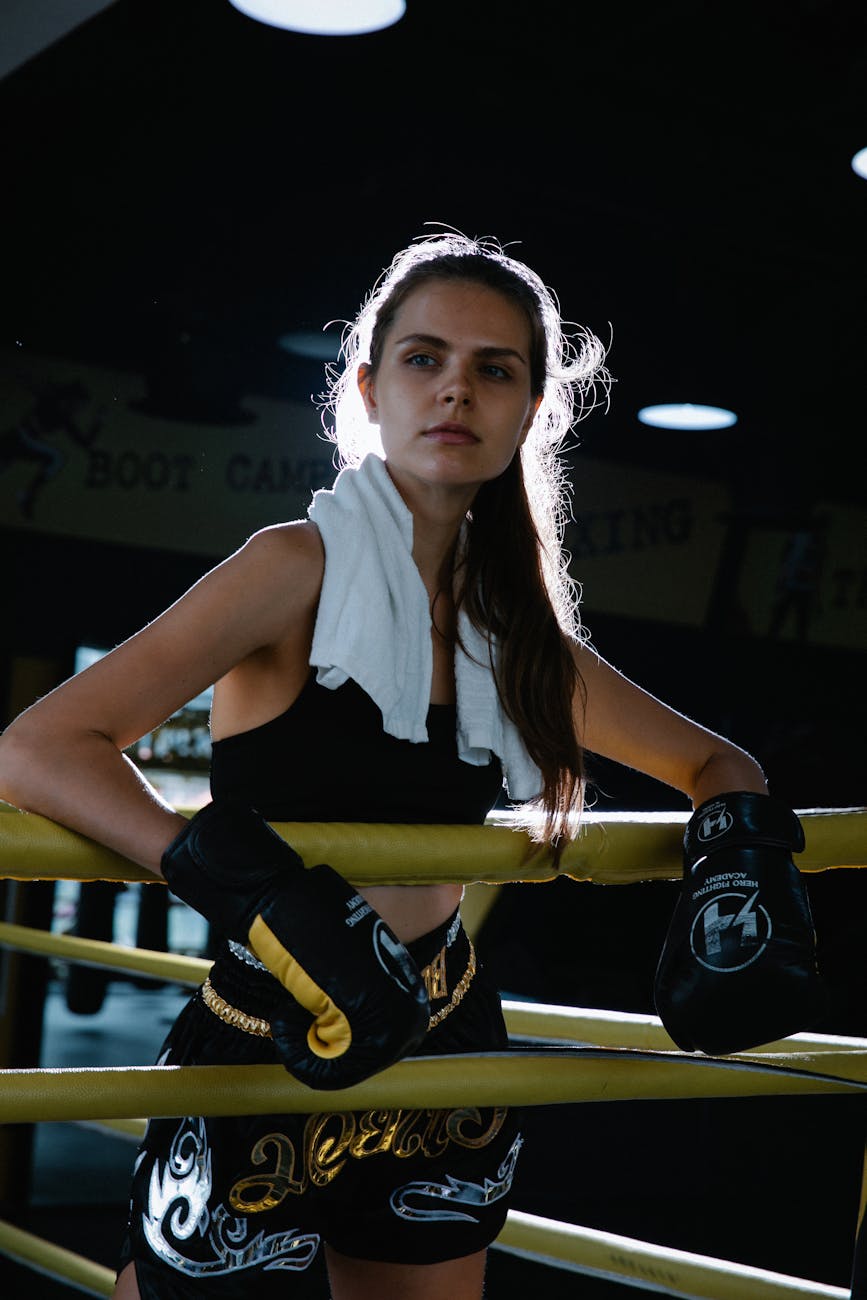 A Woman in Boxing Outfit Resting her Arms on the Ring Rope